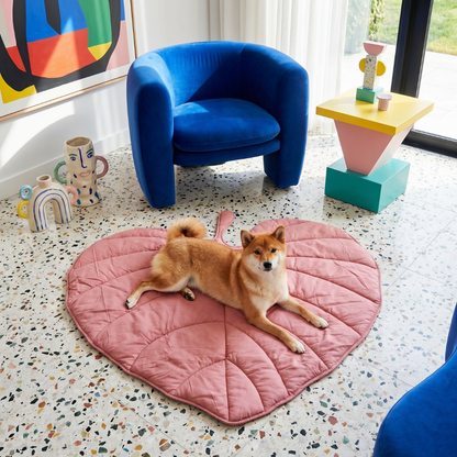 Shiba Inu dog relaxing on a pink, leaf-shaped Cloud Leaf Calming Dog Bed Mat in a modern living room.